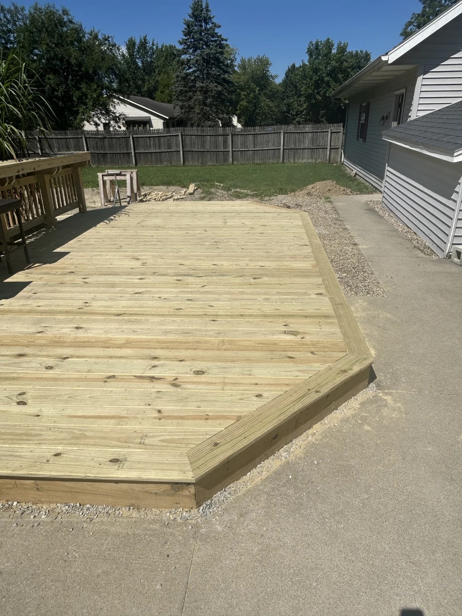 New pressure-treated deck with angled corners and a picture-frame border beside a concrete patio