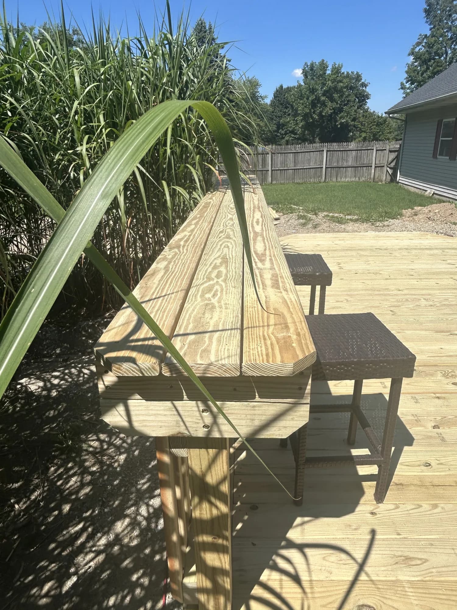 Close-up of a built-in wooden bar counter on a new deck with wicker bar stools