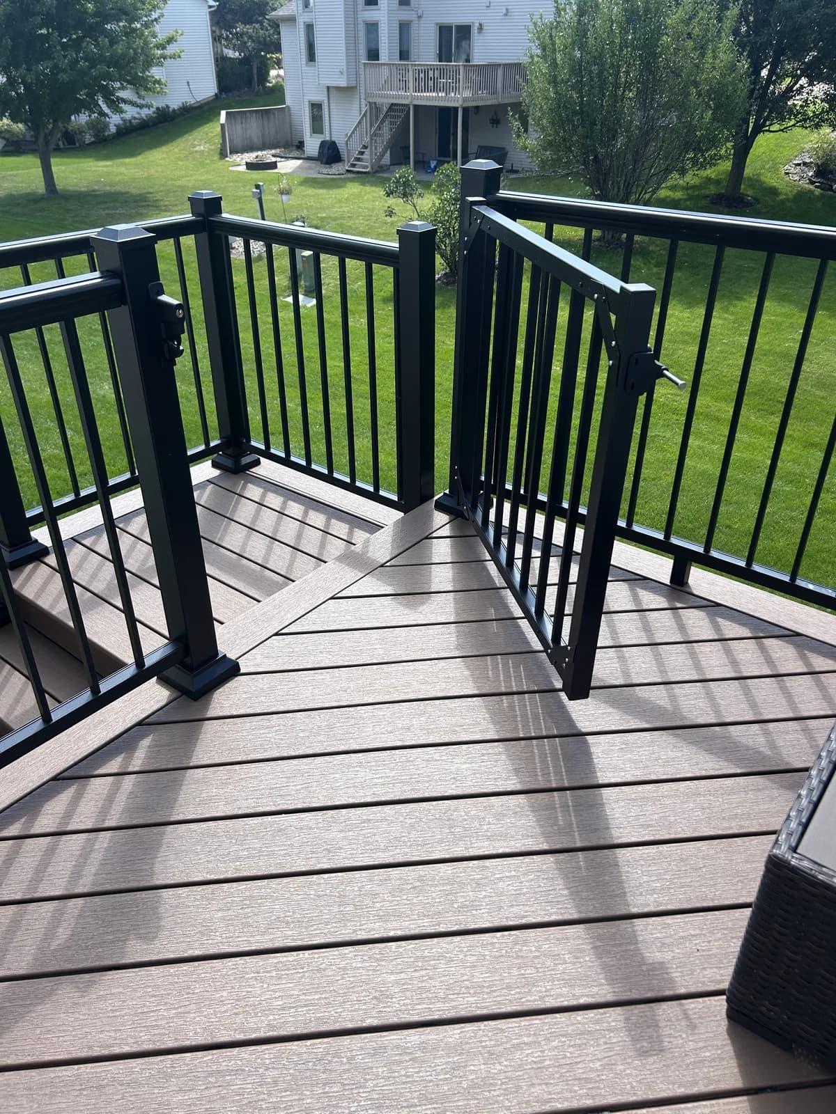Composite deck corner detail with black aluminum railings overlooking a backyard