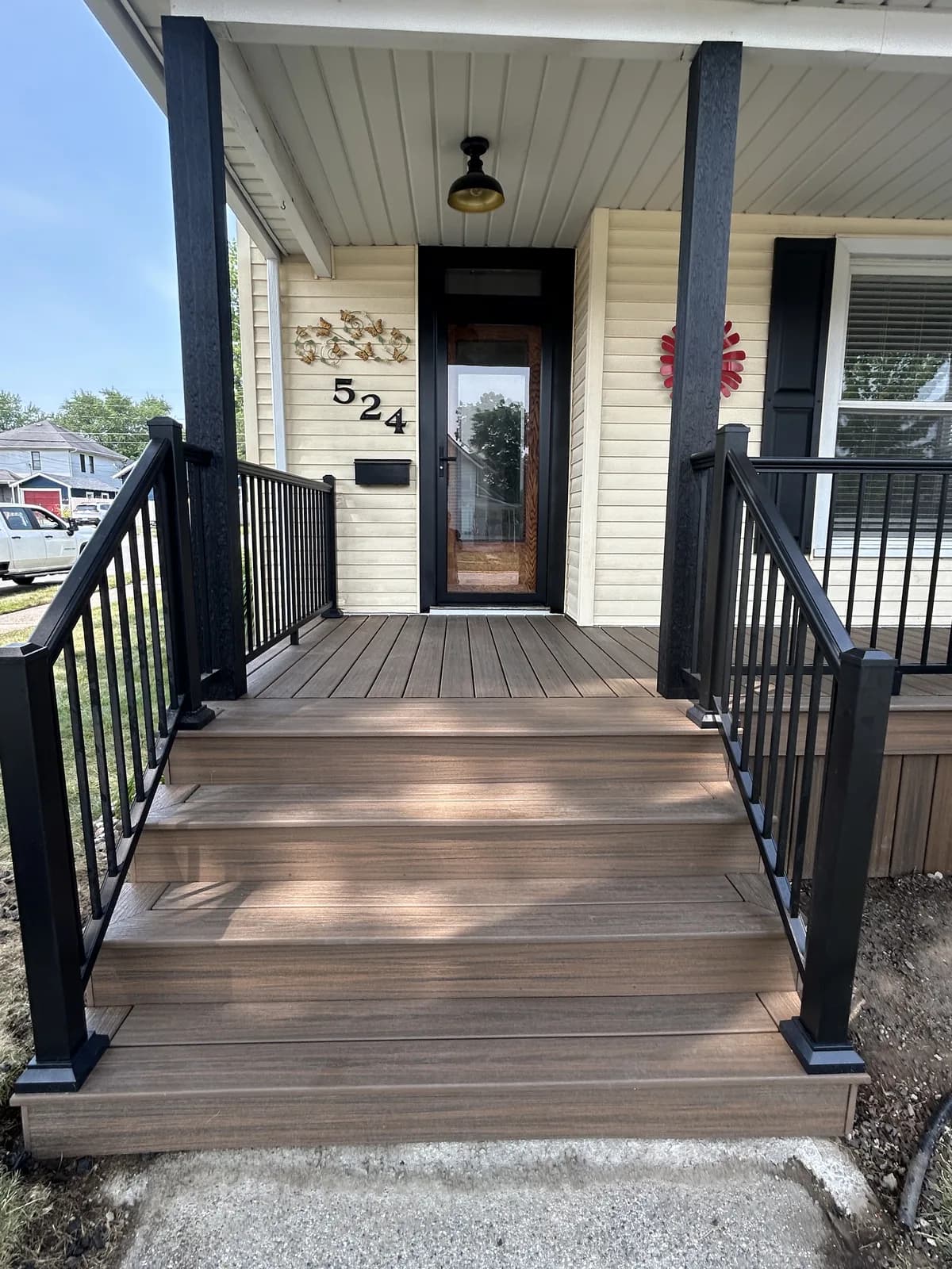 Front porch rebuilt with brown composite decking and black aluminum railings