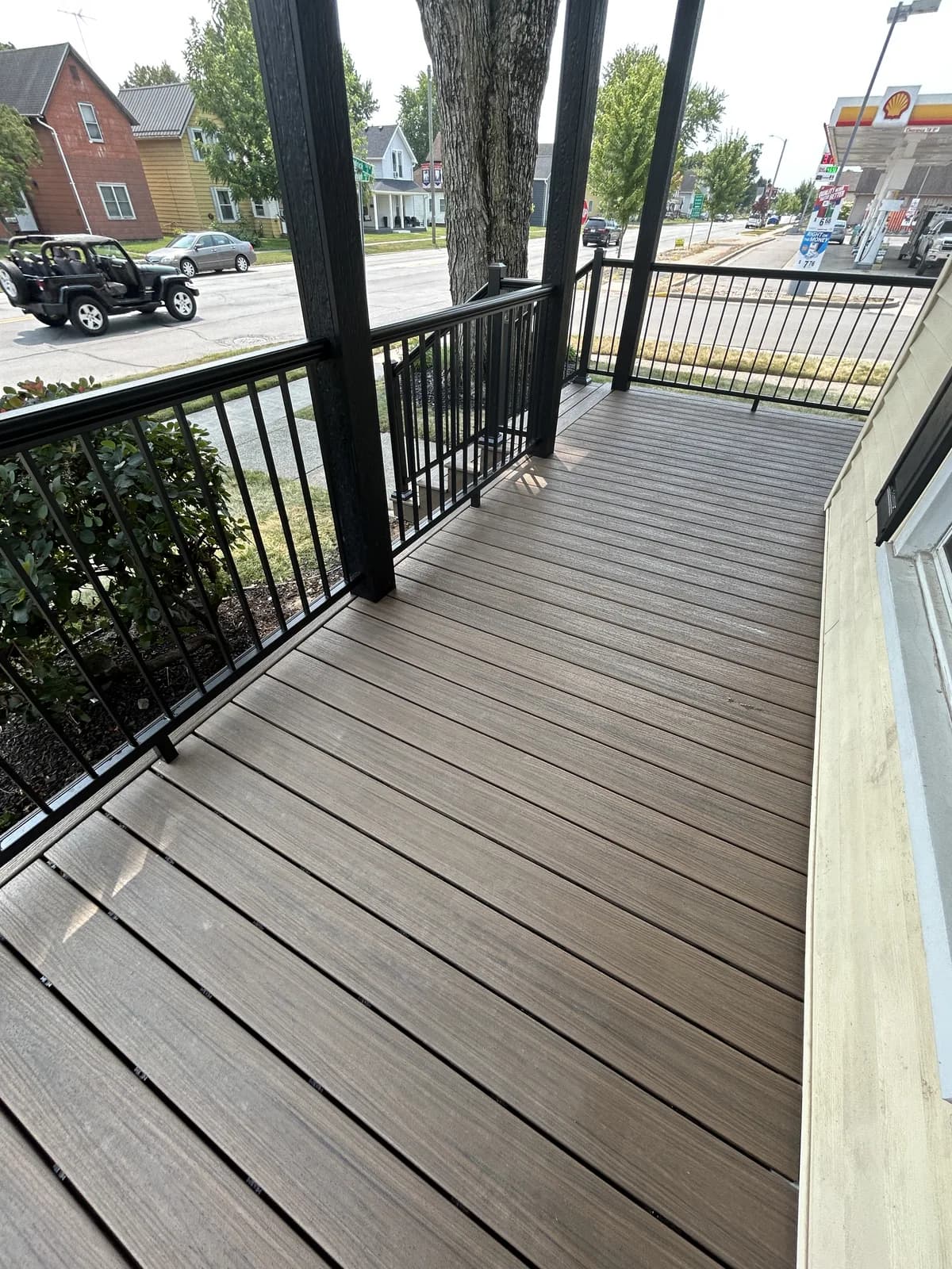 Long composite front porch walkway with black aluminum railings on a residential home
