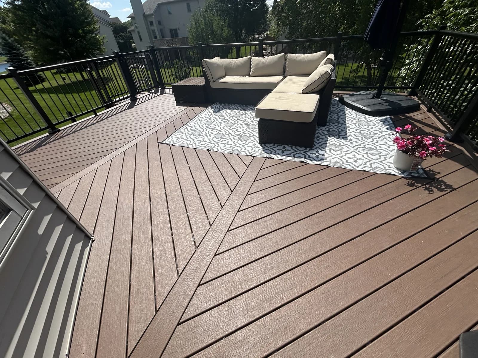 Brown composite deck laid in a diagonal pattern with black aluminum railings and patio furniture