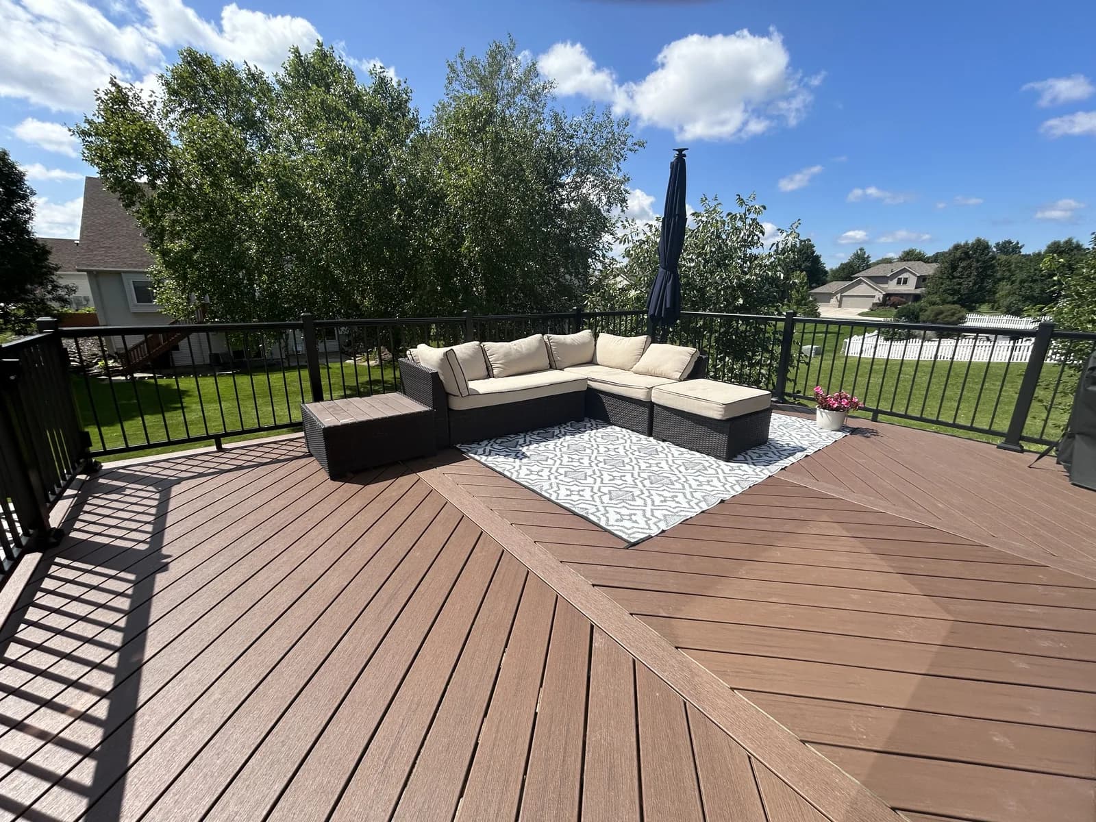 Large brown composite deck with black aluminum railings and outdoor seating in northeast Indiana