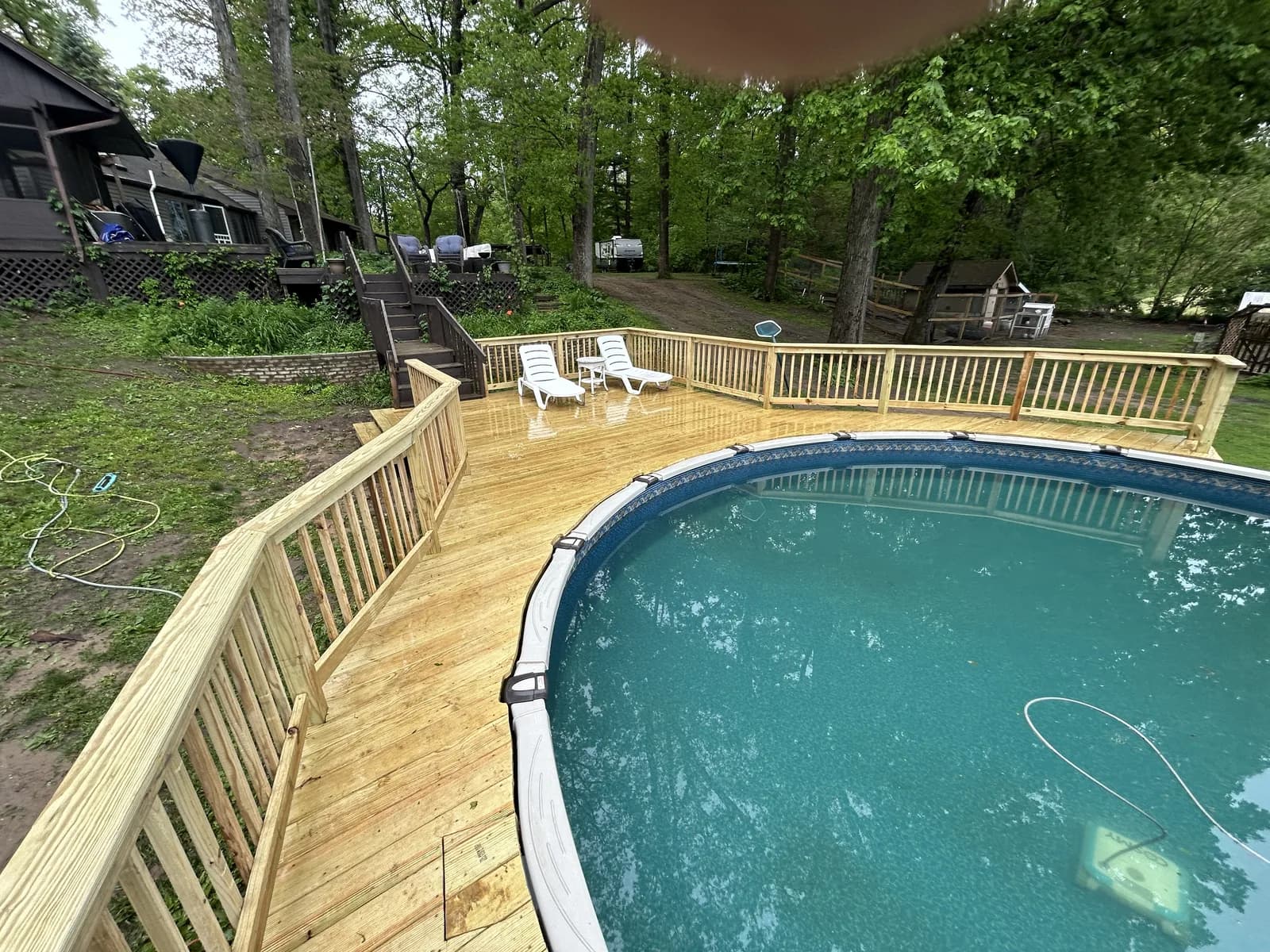 New pressure-treated wood deck wrapping around an above-ground pool in northeast Indiana