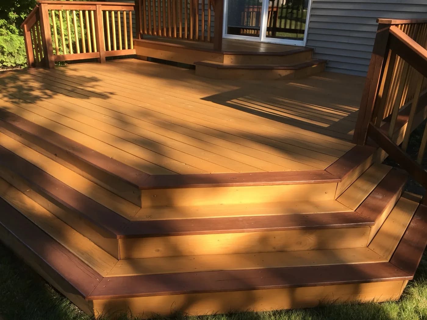 Stained cedar deck with wide cascading steps in a backyard