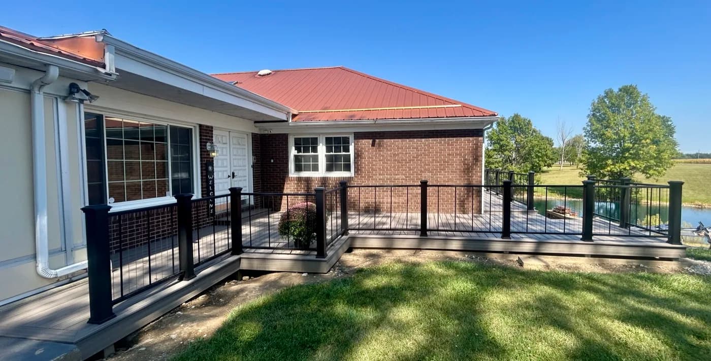 Wraparound composite deck on a brick lakehouse with black railings