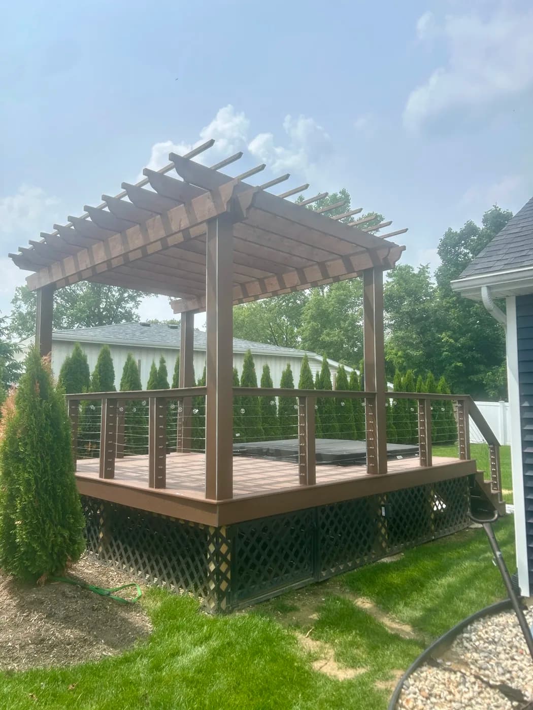 Custom pergola over a hot tub deck with cable railings and lattice skirting